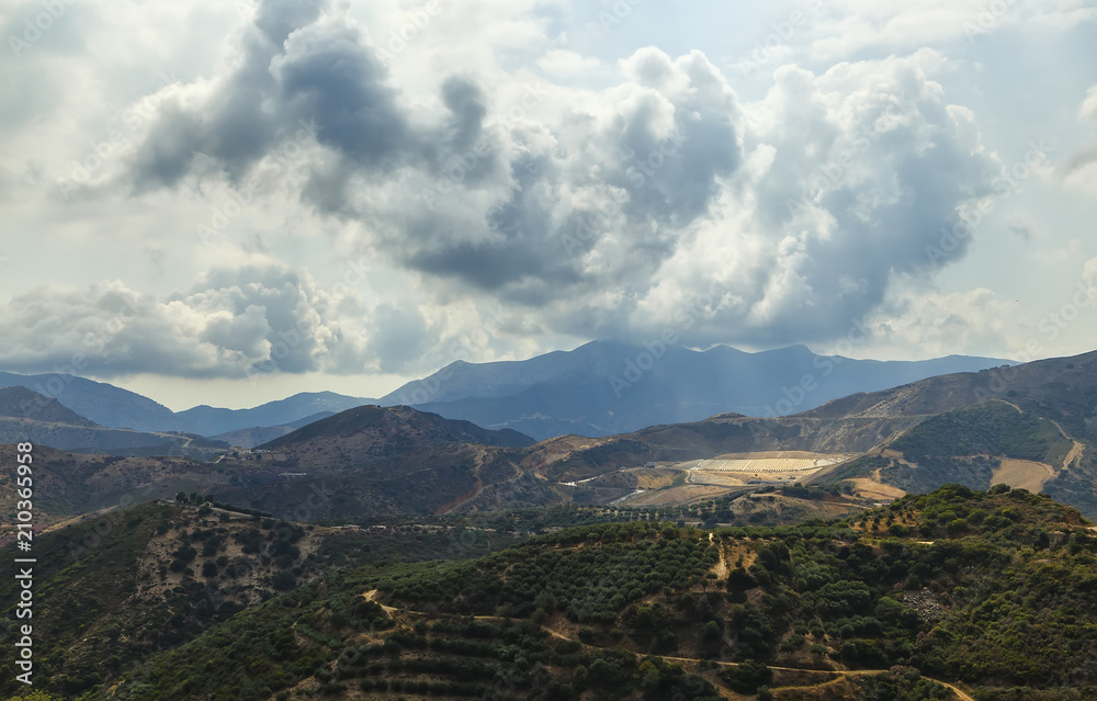 Beautiful panoramic view on dramatic stormy sky above the Cretan mountain village.Picturesque natural landscape.