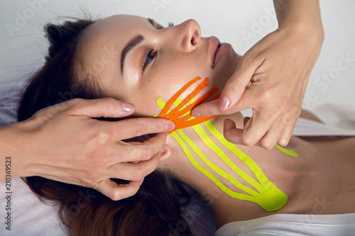 female cosmetician doing the taping of the face of the patient