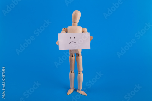 Wooding drawing figure manikin holding sign with sad face