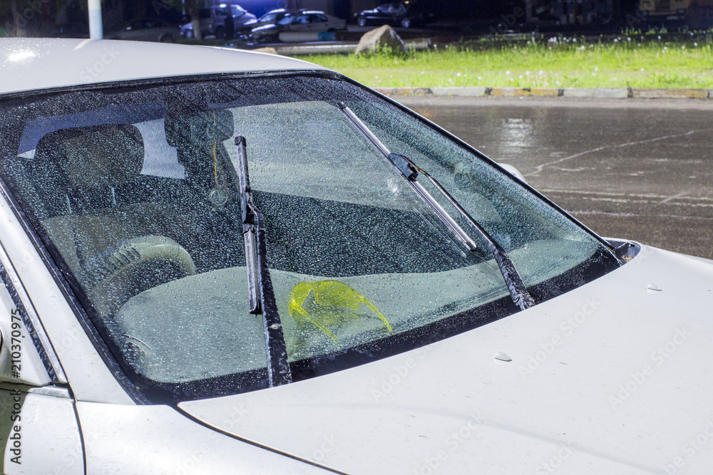 Obraz premium beautiful drops of water on the windshield of the car with the glass cleaners turned on, during a thunderstorm and rain in the night city. front and back background blurred