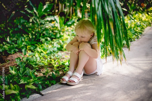 
girl hid under a palm leaf. Reuniting with nature. Childhood, lifestyle. 