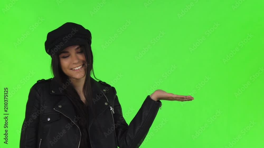 Studio shot of a beautiful long haired brunette young woman wearing stylish black outfit, smiling to the camera, holding copy space on her hand. Advertising concept. Studio shot of a beautiful long haired brunette young woman wearing stylish black outfit, smiling to the camera, holding copy space on her hand. Advertising concept.