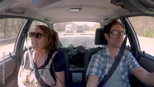 Happy woman passenger listening to music with a male driver in a car photo