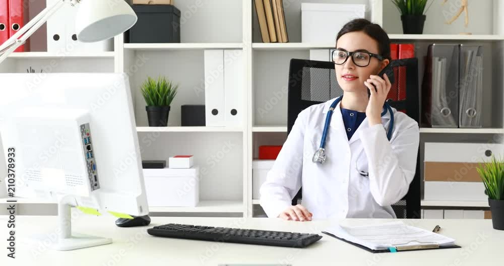 doctor talking on phone and looking at monitor. doctor talking on phone and looking at monitor.