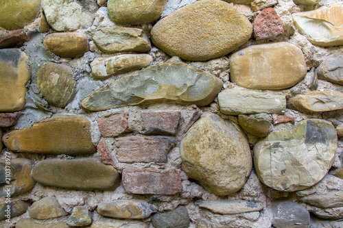 Handmade cobble stone texture wall with different sizes of materials.Fragment of the cobblestone wall.Italy