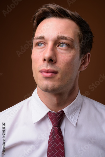 Young handsome businessman against brown background