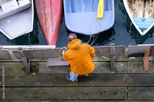 Fisherman on dock with boats in orange jacket © Patrick