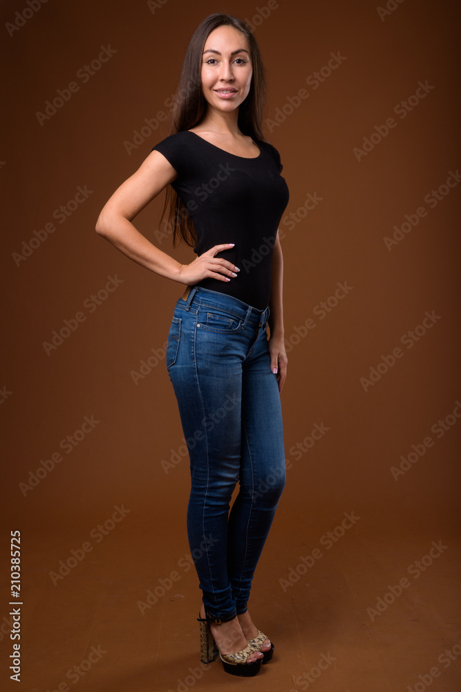 Studio shot of young beautiful woman against brown background Studio shot of young beautiful woman against brown background