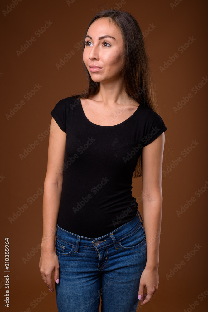 Studio shot of young beautiful woman against brown background Studio shot of young beautiful woman against brown background
