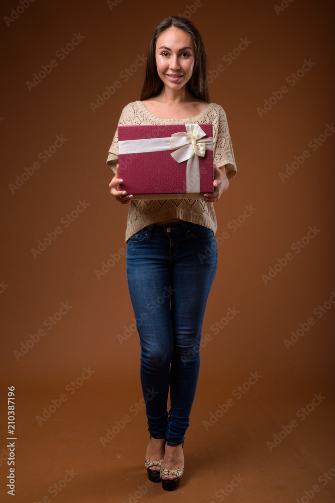 Studio shot of young beautiful woman against brown background Studio shot of young beautiful woman against brown background