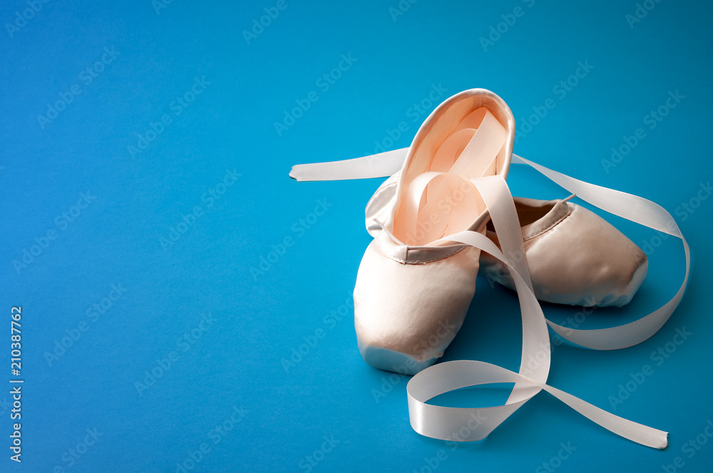 Fototapeta premium Ballet dancing concept with a pair of silk shoes isolated on minimalist bright blue background