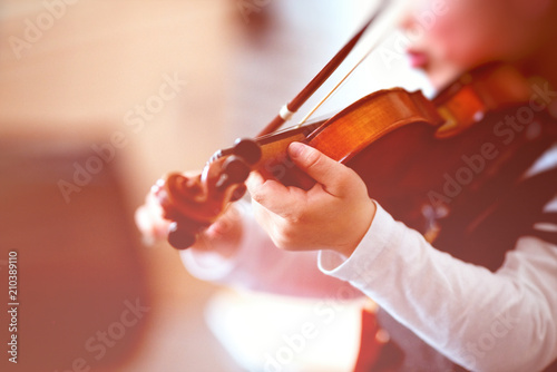 Child playing the violin in a room
