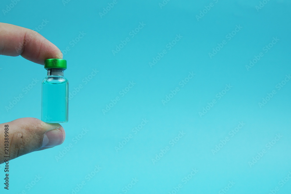 Selective focus a hand holding a vial with blue background. Selective focus a hand holding a vial with blue background.