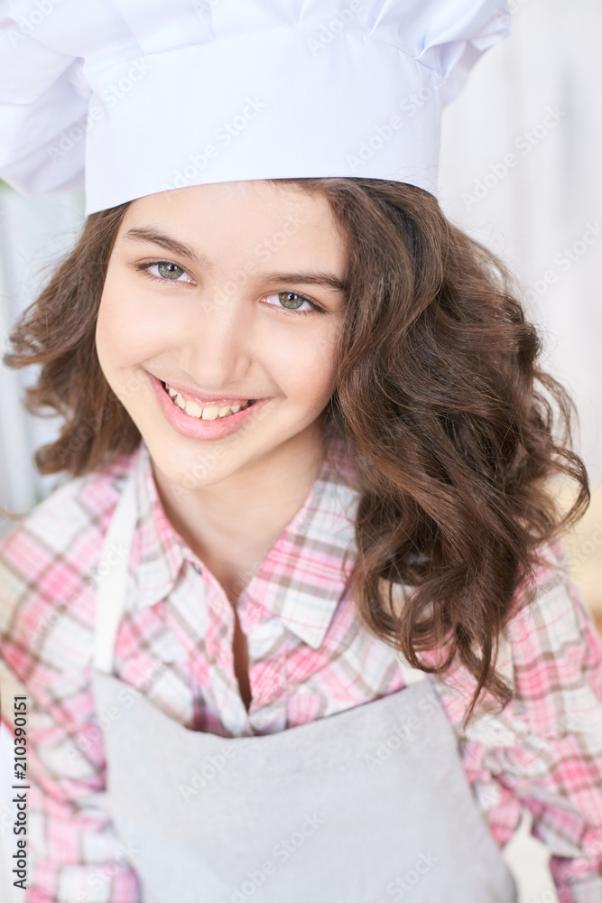 Little cook. Beautiful girl. White cap. Brown curly hair Little cook. Beautiful girl. White cap. Brown curly hair