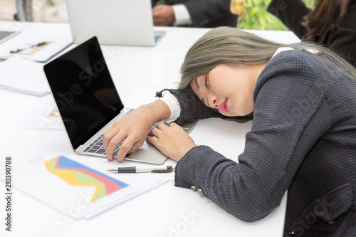 Tired businessman working late at the office. Beautiful woman sleeping on her desk in meeting room.