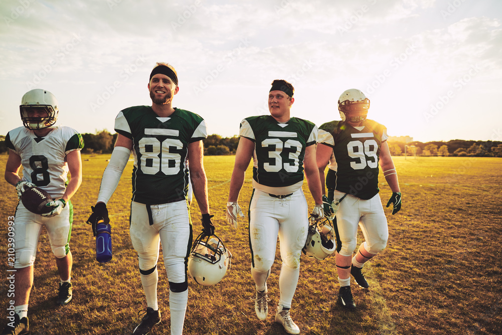 Smiling team of American football players walking off a field Stock