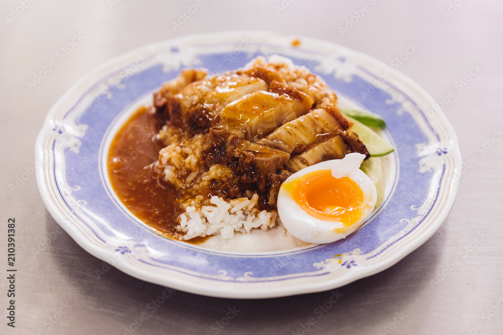 Crispy pork belly with rice pouring with gravy served with half of boiled egg. Crispy pork belly with rice pouring with gravy served with half of boiled egg.