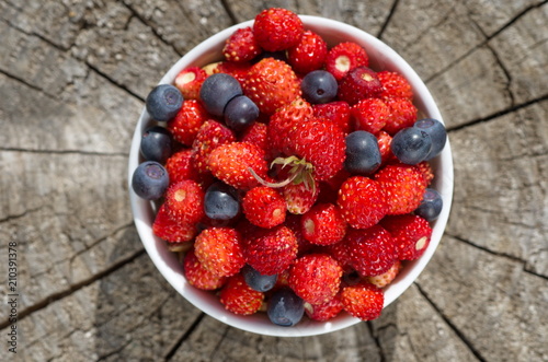 Bowl with strawberries and blueberries on a wooden background close-up