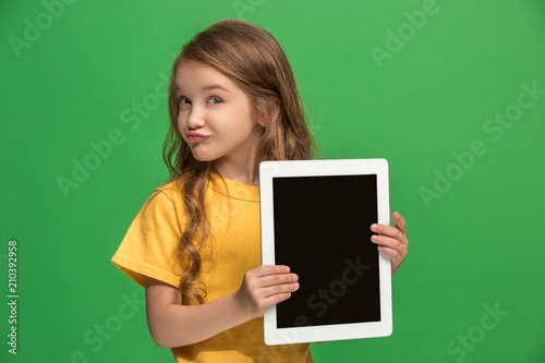 Little funny girl with tablet on green background