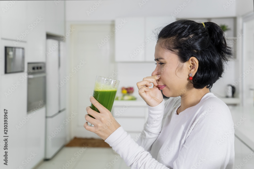 Disgusted woman drinking healthy juice Disgusted woman drinking healthy juice