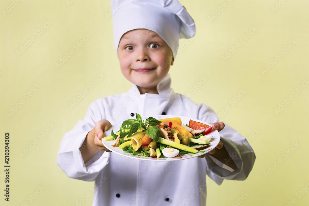 funny boy chef cooked salad with vegetables, cheese and ham on a plate funny boy chef cooked salad with vegetables, cheese and ham on a plate