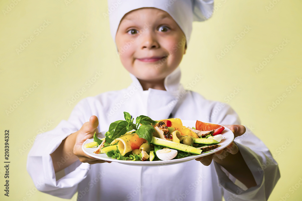 funny boy chef cooked salad with vegetables, cheese and ham on a plate funny boy chef cooked salad with vegetables, cheese and ham on a plate