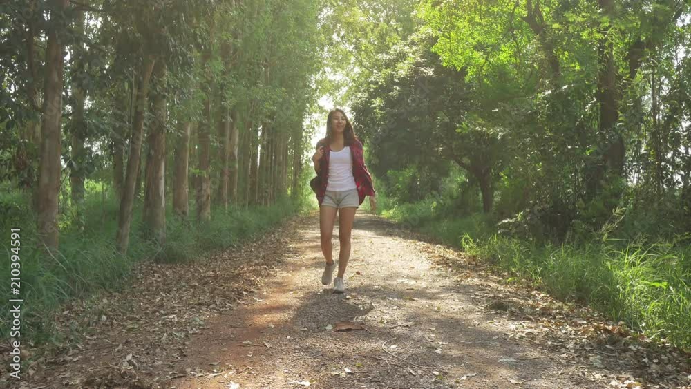 Happy young Asian woman traveler with backpack walking in forest. Hiker Asian woman with backpack walking on path in summer forest. Adventure backpacker travel people concept. Happy young Asian woman traveler with backpack walking in forest. Hiker Asian woman with backpack walking on path in summer forest. Adventure backpacker travel people concept.