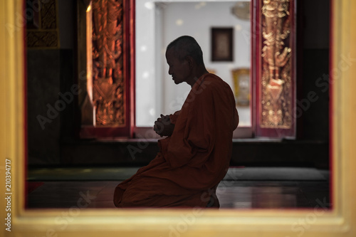 Thai Buddhist monk chanting and praying inside an old temple