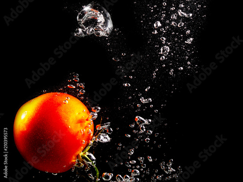 Red tomato in water on a black background