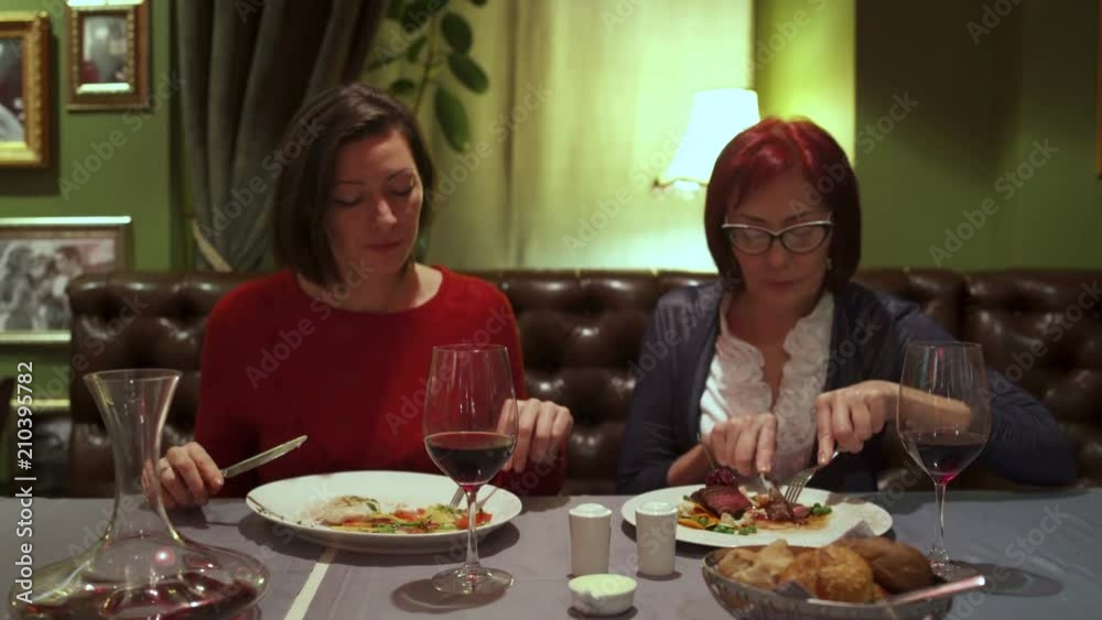 Women sitting at a table in the restaurant and eat salad and beef steak. Women sitting at a table in the restaurant and eat salad and beef steak.