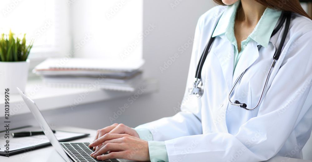 Close up of unknown female doctor sitting at the table near the window in hospital Close up of unknown female doctor sitting at the table near the window in hospital