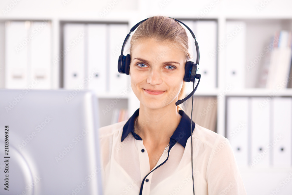 Call center operator. Blonde business woman in a headset in white office with pc computer Call center operator. Blonde business woman in a headset in white office with pc computer