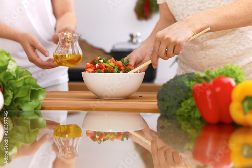 Closeup of human hands cooking in kitchen. Mother and daughter or two female friends cutting vegetables for fresh salad. Healthy meal  vegetarian food and lifestyle concepts