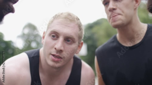 Group of sportsmen have a pep talk huddle and put hands together, in slow motion 