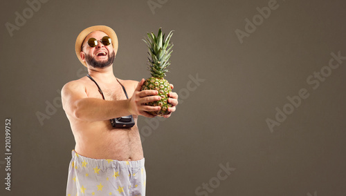 Funny fat bearded man with a pineapple on vacation in the summer. photo