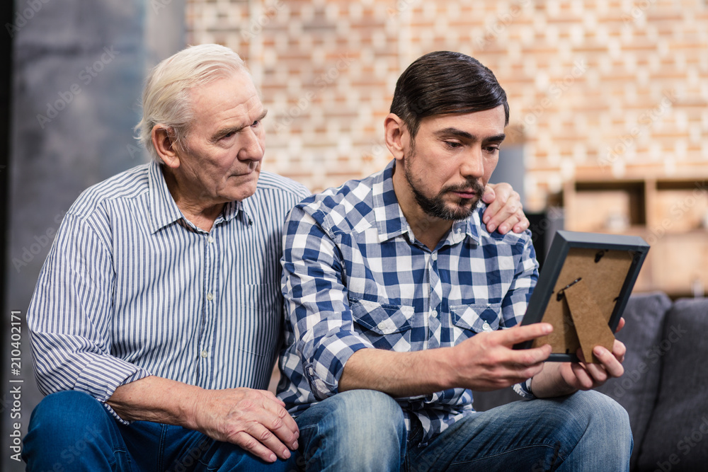 Sad bearded man holding a photo frame Sad bearded man holding a photo frame
