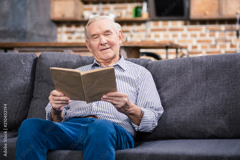 Nice senior man reading a book at home