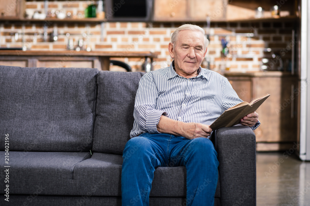 Pleasant aged man reading books at home