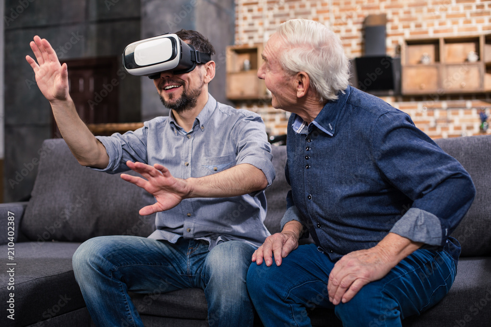 Positive man using VR device with his father