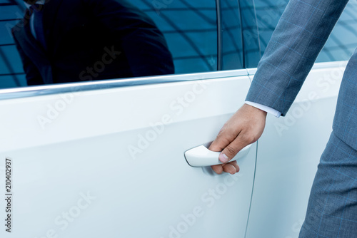 cropped shot of businessman opening car door on street
