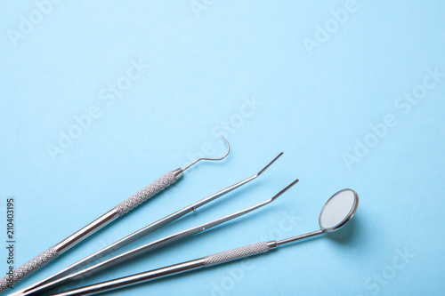 Dental instruments. Dental mirror  probe hook  tweezers on blue background