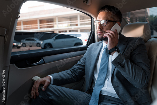 businessman talking on smartphone on backseat in car © LIGHTFIELD STUDIOS