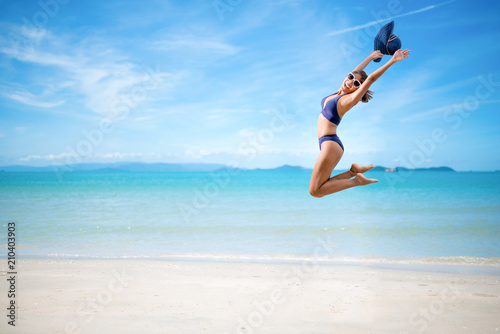 Sexy woman in the blue bikini jumping on beach