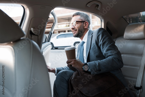 businessman with coffee to go sitting in car with opened door © LIGHTFIELD STUDIOS