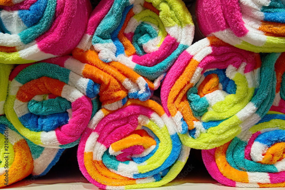 Colorful towels rolled and stacked on shelf