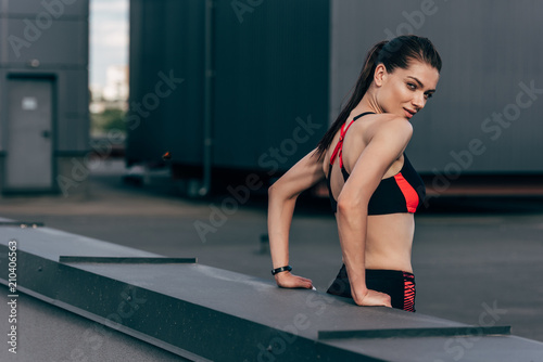 young sportswoman in sportswear on roof in city