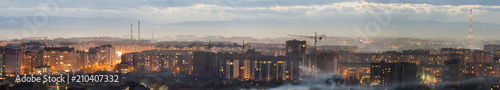 Panorama of night aerial view of Ivano-Frankivsk city, Ukraine. Scene of modern night city with bright lights of tall buildings. Residential quaters and construction cranes in modern urban space. photo