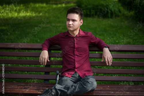 A young man sits on a bench, waiting for someone