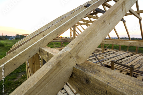 New wooden ecological house from natural materials under construction. Close-up detail of attic roof frame against clear sky from inside. Building, roofing, construction and renovation concept.