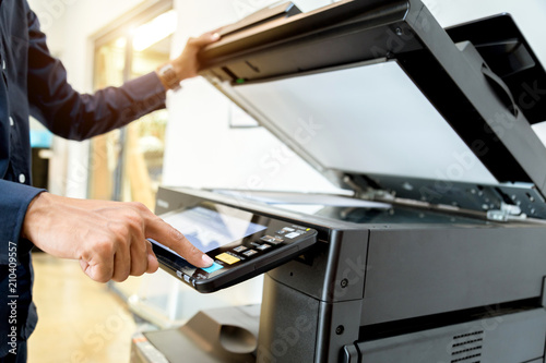 Bussiness man Hand press button on panel of printer, printer scanner laser office copy machine supplies start concept. photo